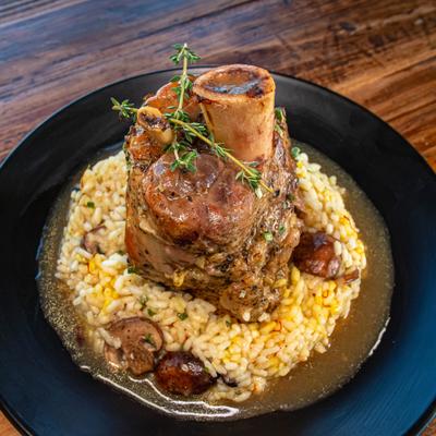 Osso buco served over mushroom risotto in a black bowl