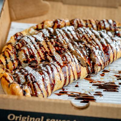 Dessert calzone topped with chocolate drizzle and powdered sugar.