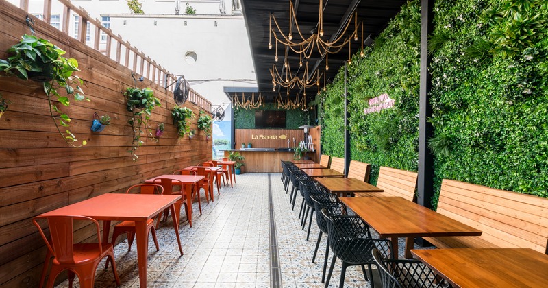 Patio, left and right line od tables and chairs, green plant wall