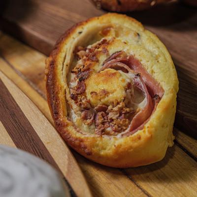 A close-up of a savory pastry roll filled with ham and cheese.