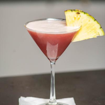 Red cocktail, with pineapple garnish.