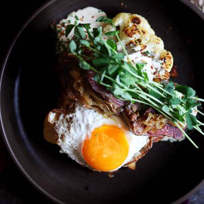 Colorado Corned Beef topped with a sunny-side-up egg and herbs.