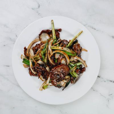 Mongolian beef and vegetable stir fry served on white plate.
