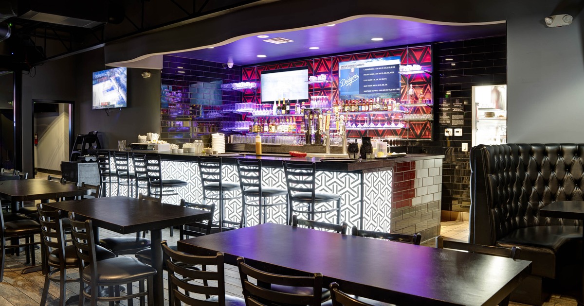 Modern bar area with illuminated patterned counter, bar stools, and dining tables