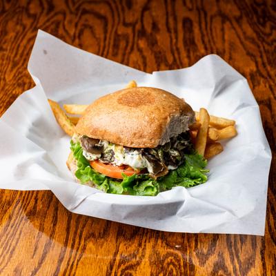 Grilled chicken sandwich with goat cheese, mushrooms, lettuce, tomato, and fries.