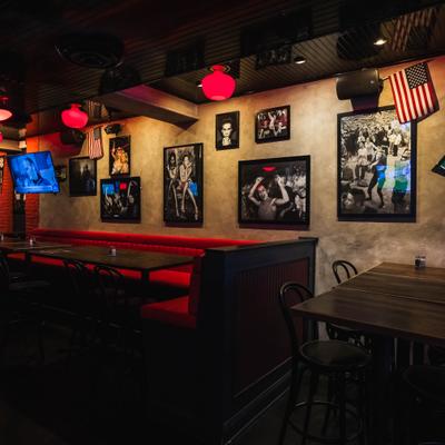 Dimly lit restaurant with red booths, red pendant lights, and framed photographs.