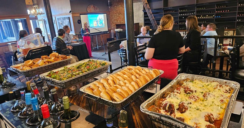 A buffet table in a room with people gathered for an event