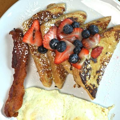 French Toast with berries, fried eggs, and bacon.