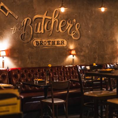 Interior with leather tufted booth seating, wooden tables and wall signage.
