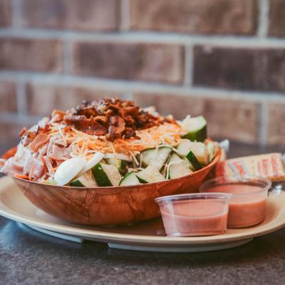 Chef salad accompanied by dressings and crackers.