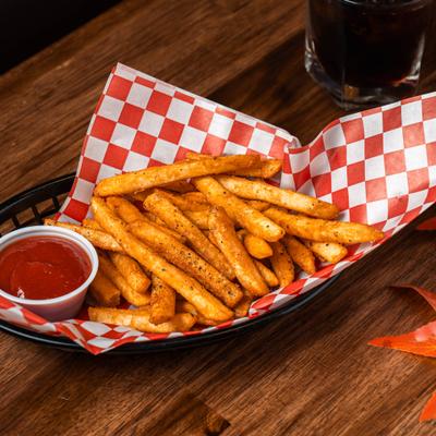 Fries served in a basket lined with red-and-white checkered paper with a side of sauce.