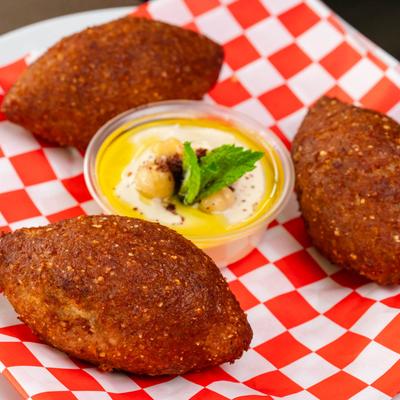 Kibbeh accompanied with hummus or a similar dip.