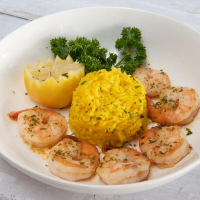 Shrimp and yellow rice with lemon and green garnish.