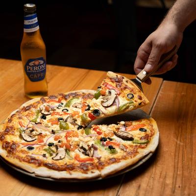 Veggie pizza and beer,  the pizza slice being lifted.