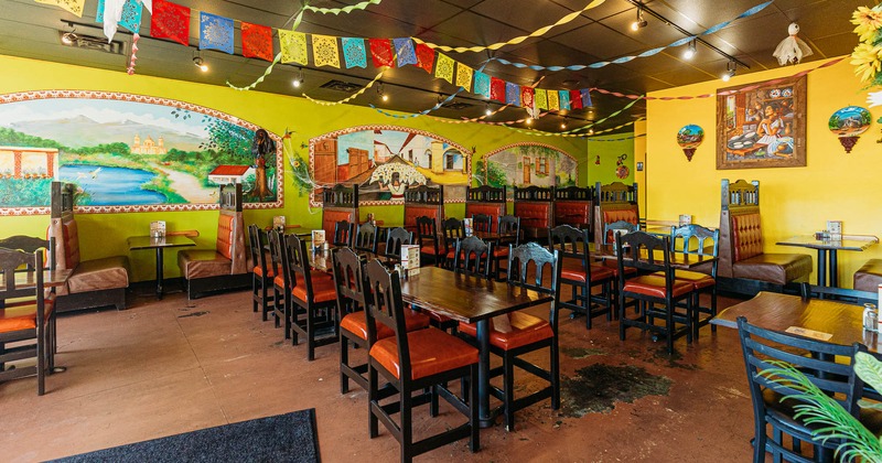 Dining area, walls decorated with mural art and paintings, fiesta banners