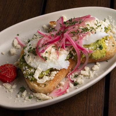Avocado toast with cheese, pickled red onions, and' two poached eggs.