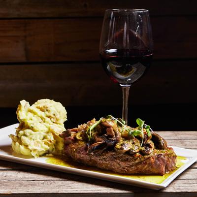The New York strip topped with mushroom sauce, served with mashed potatoes and red wine.