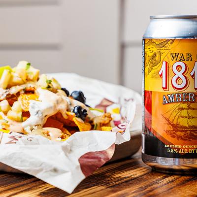 Loaded nachos beside a can of house-brewed beer.
