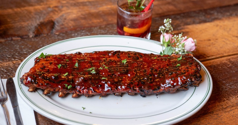 BBQ spare ribs garnished with flowers, served with a cocktail