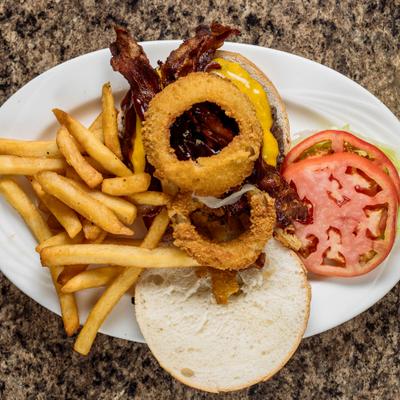 Bacon cheeseburger with onion rings, BBQ sauce, lettuce, tomato, and fries.