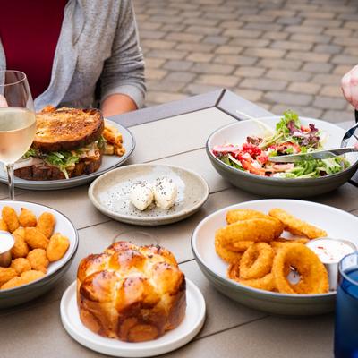 Patio table spread with sandwiches salads and fried sides.