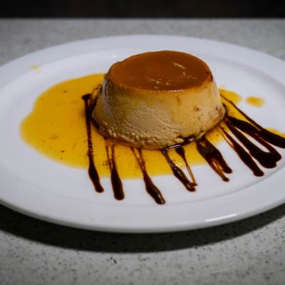 Flan served on a plate with caramel sauce and chocolate sauce drizzle.