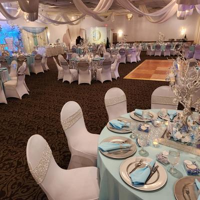 Banquet hall with blue and silver wedding decorations, round tables, and elegant event setup.