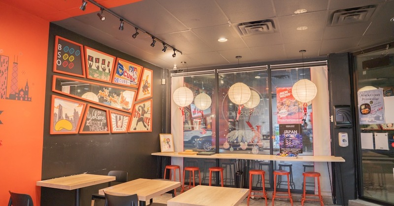 Dining room with wall art, tables,  paper lanterns and window counter with stools