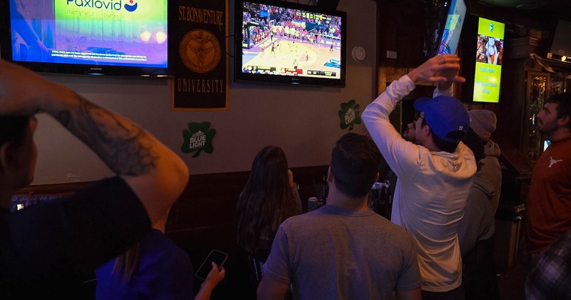 Bar, bartender, guests, game on tv above
