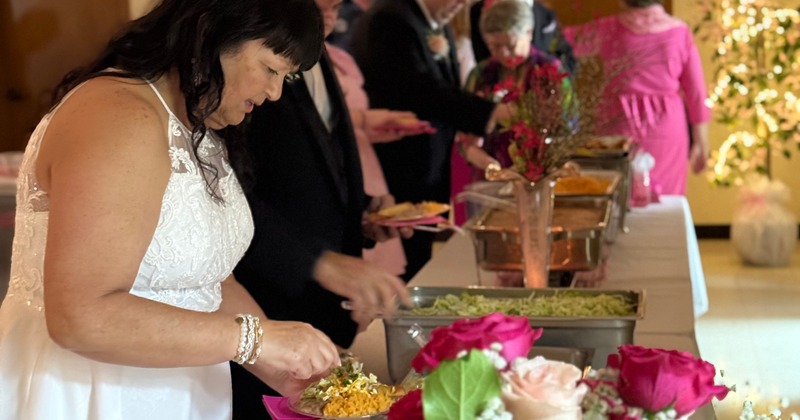 Bride serving herself food at a buffet line