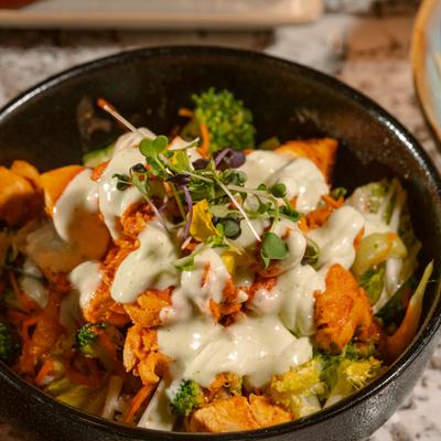 Buddha Bowl drizzled with creamy sauce and topped with microgreens, close-up.