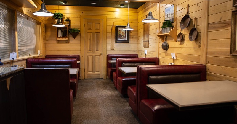 Booths with tables on both sides of the room, the wooden wall behind
