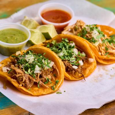 Pulled pork tacos, with cilantro and onion, served with salsa.