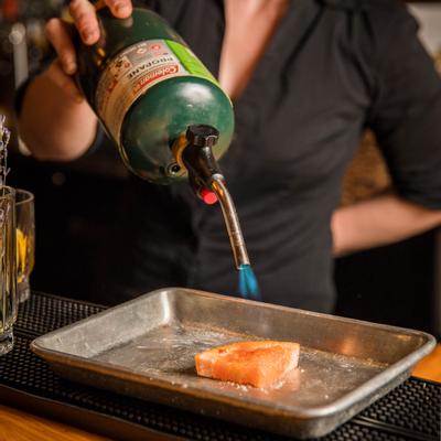 Bar staff burning citrus wedge with kitchen torch
