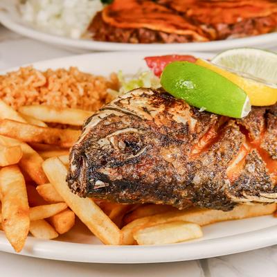 Grilled fish served with grilled peppers, onions, rice, fries, and salad.