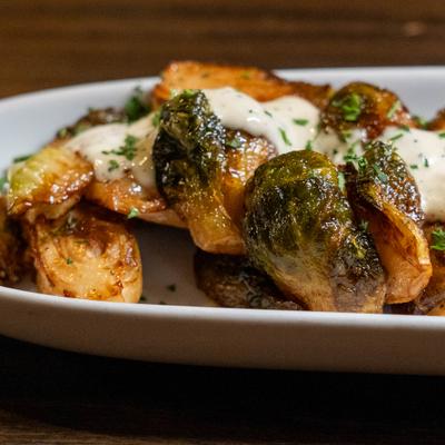 Crispy Brussels sprouts topped with creamy sauce and herbs.