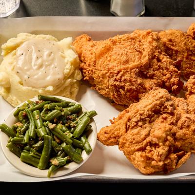 Fried chicken plate with sides of green beans and mashed potatoes.