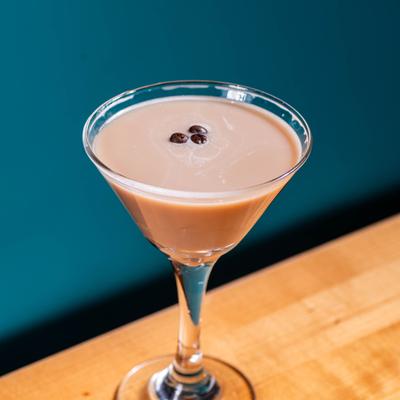 Espresso Martini served in a martini glass with coffee beans as garnish.