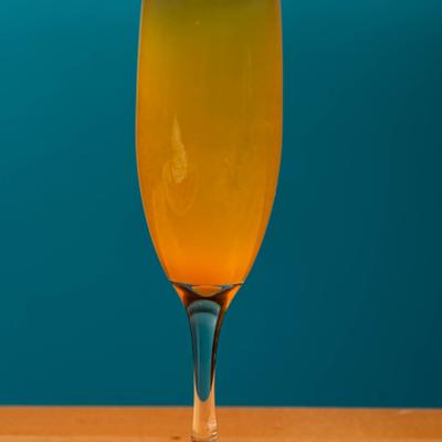 Mimosa flute glass on a wooden table with a blue background.