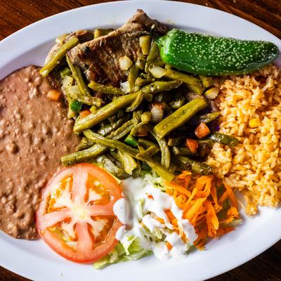 Carne asada with cactus, rice, refried beans, and salad.