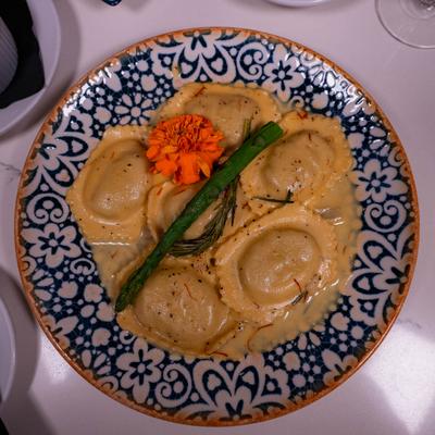 Creamy ravioli garnished with asparagus and an orange flower.