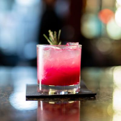 Blueberry refresher drink with ice and a green herb garnish.