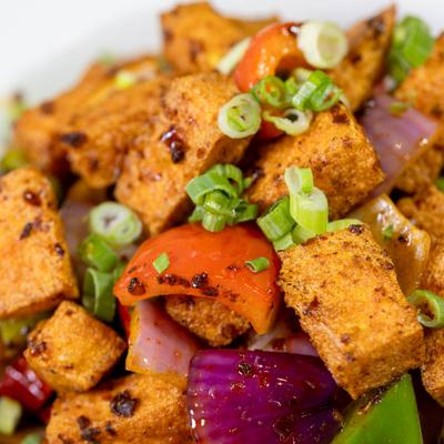 Crispy tofu with scallions, peppers, tomatoes, and onions.