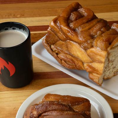 Glazed caramel apple pull-apart bread served with a mug of milky hot beverage.
