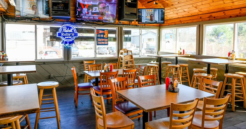 Interior, seating area, wooden top tables with chairs, large window area, TVs on the wall