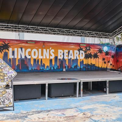 Ourdoor stage with a mural on the back wall and signage.