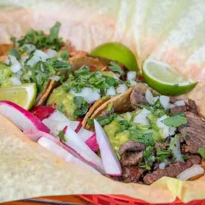 Carne asada tacos with guacamole, cilantro, and onions.