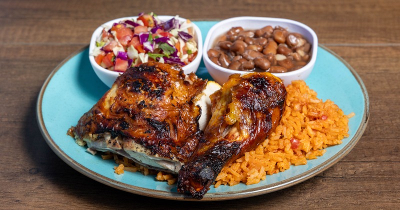 Roasted chicken served with Mexican rice, black beans and a salad