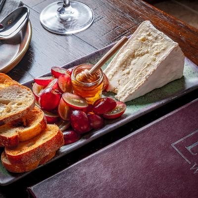 Burgundy board featuring grapes honey cheese and bread.