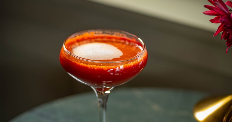 Cocktail served in a coupe glass with a vibrant red hue